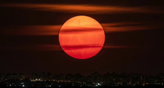 Superlua com tom avermelhado sobre cidade noturna, simbolizando a lua sangue e a superlua no céu brasileiro