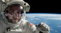 Close-up de um astronauta sem capacete no espaço, com pele translúcida e corpo inchado, ilustrando que acontece corpo humano